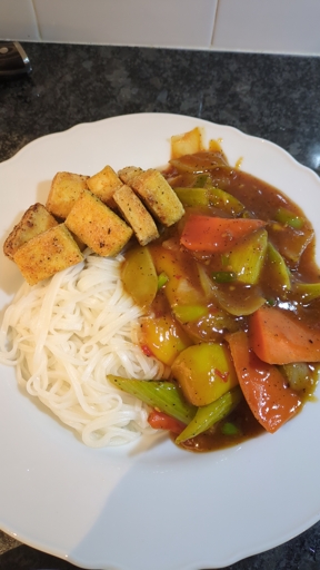 plate of rice noodles and cubed crispy tofu with veggies in a glaze sauce